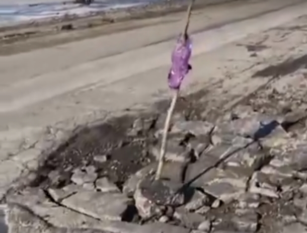 Вместо ремонта трассы Ростов-Волгодонск работники установили в яме предупреждающую палку с намотанным фиолетовым пакетом